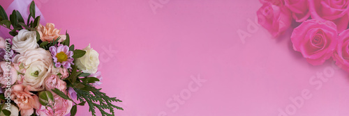 Banner. View from above. On a bouquet of roses  ranunculus  carnation  juniper  eustoma  bush chrysanthemum on a pink background in the lower corner. With a space to copy. High quality photo