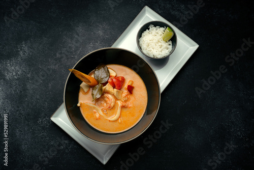 Thai soup with seafood and rice, on dark concrete