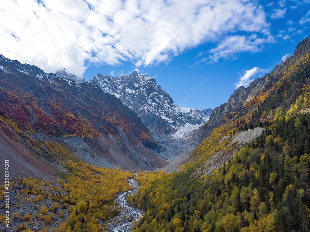 Beautiful, delightful autumn view from a drone of the mountains, the river, the Chalaadi glacier on a sunny day. Very beautiful autumn landscape of the mountains