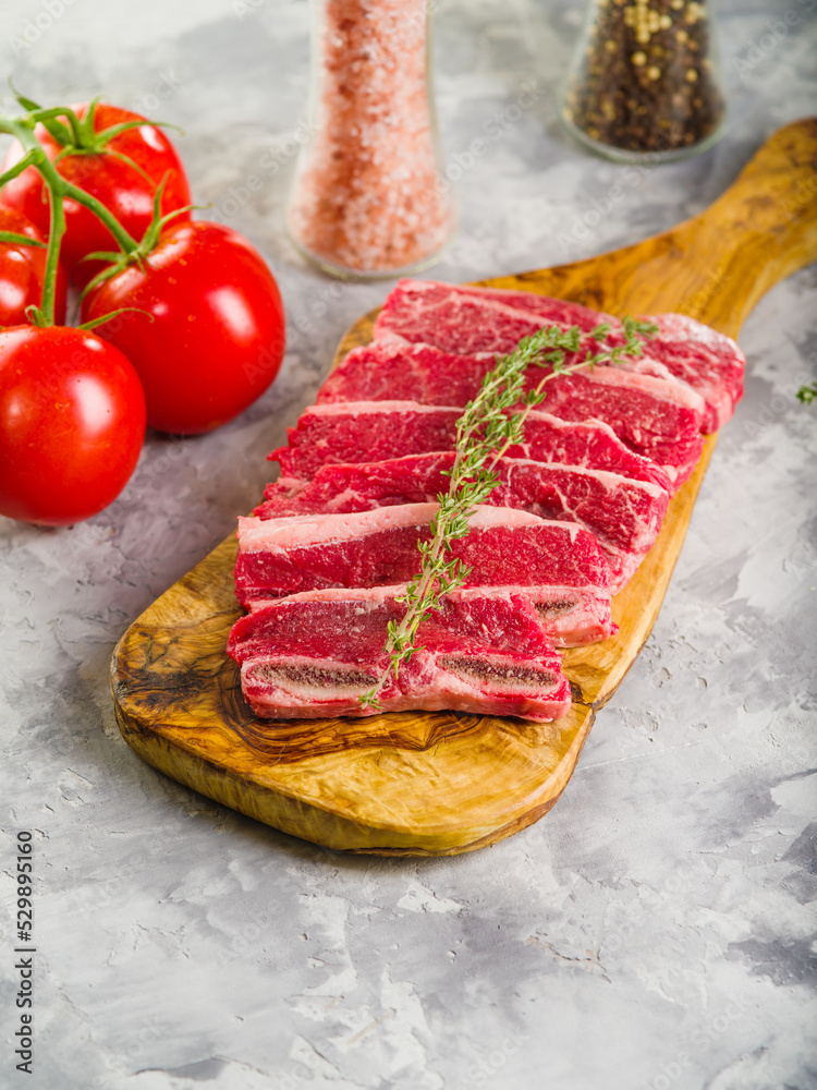 Homemade meat raw steaks on a cutting board, tomatoes, rosemary sprig, spices. Food background. There are no people in the photo. Culinary blog, recipe book.