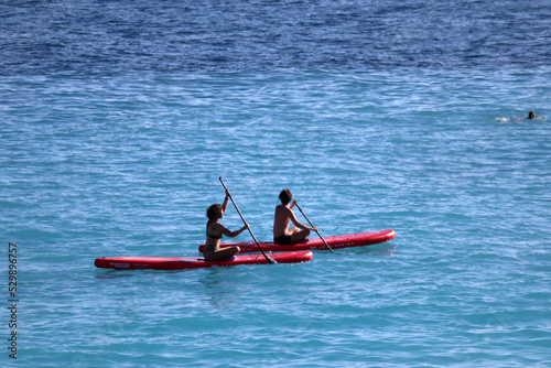 Nice, France - 28.08.2022 : Man and woman learning to paddle in the Bay of Nice, French riviera