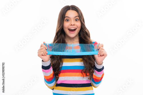 Teen girl girl with brush combing hair. Girl taking haircare and hairstyle. Hairdresser hair solon for teenager. Excited face  cheerful emotions of teenager girl.