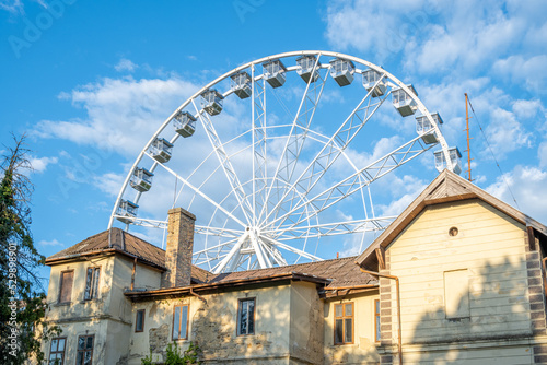 Ferris wheel detail and the part of the house in front against blue sky in Keszthely, Hungary