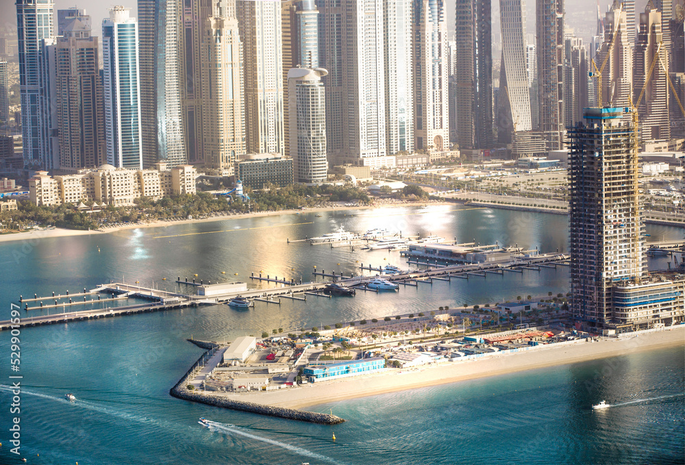 Fototapeta premium Dubai, UAE. Dubai Marina yachts pier view at sunset with beautiful golden reflection in the water