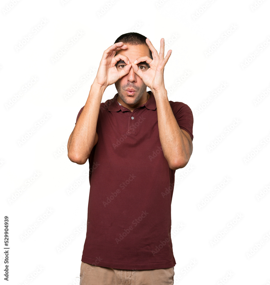 Amazed young man using his hands like a binoculars Amazed young man using his hands like a binoculars