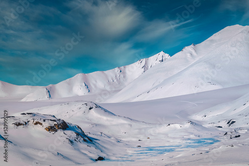 2022-09-10 SNOW COVERED MOUNTAIN RANGE WITH A SMALL GALCIER AND EWXPOSED ROCKS ON SVALBARD NORWAY IN THE ARCTIC photo