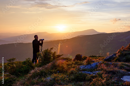 Canvastavla Photographer with the tripod takes photos of the mountains at the sunset
