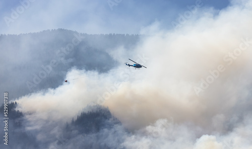 Wildfire Service Helicopter flying over BC Forest Fire and Smoke on the mountain near Hope during a hot sunny summer day. British Columbia, Canada. Natural Disaster © edb3_16