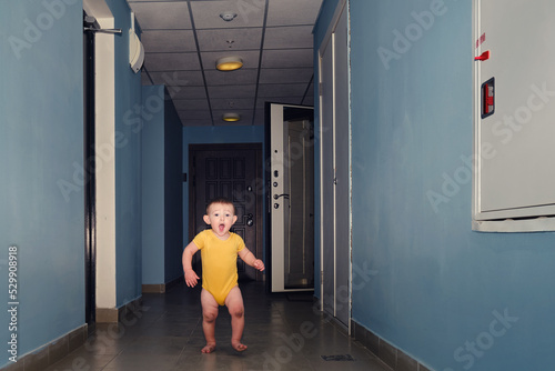 Toddler baby leaves the open door of the apartment. Child boy runs away from home. Kid age one year © Андрей Журавлев