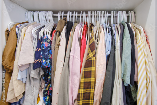 Open closet with women s clothes on a hanger, female dresses and shirts are hung in the wardrobe