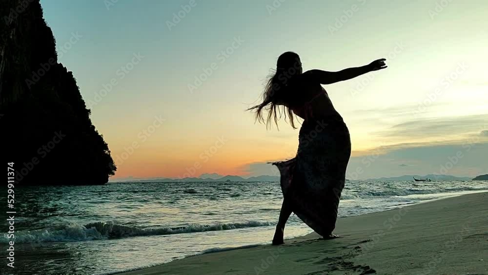 Mujer bailando en playa tailandesa al atardecer