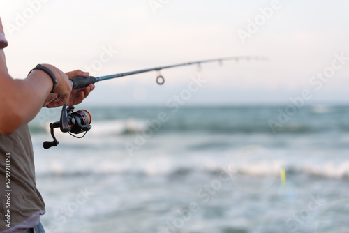 Man throwing fishing rod into the sea at the pier