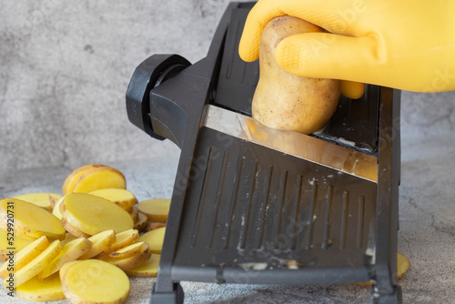 Εκτύπωση καμβά Person slicing potato on a kitchen mandolin cutter