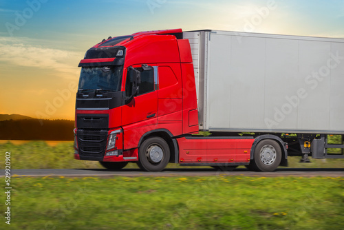 Red Truck Moves Along Country Road in summer.