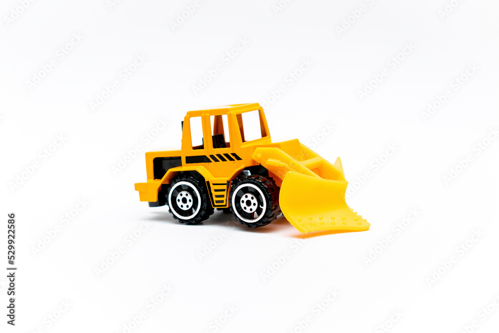 Naklejka premium Colorful little mini yellow plastic tractor, truck, lorry, car toy isolated on white background mockup with copy space, toys for children, kids development, playing, childhood fun