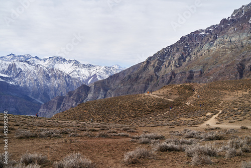 group of people walking the trail of a hill in the middle of the andes chile