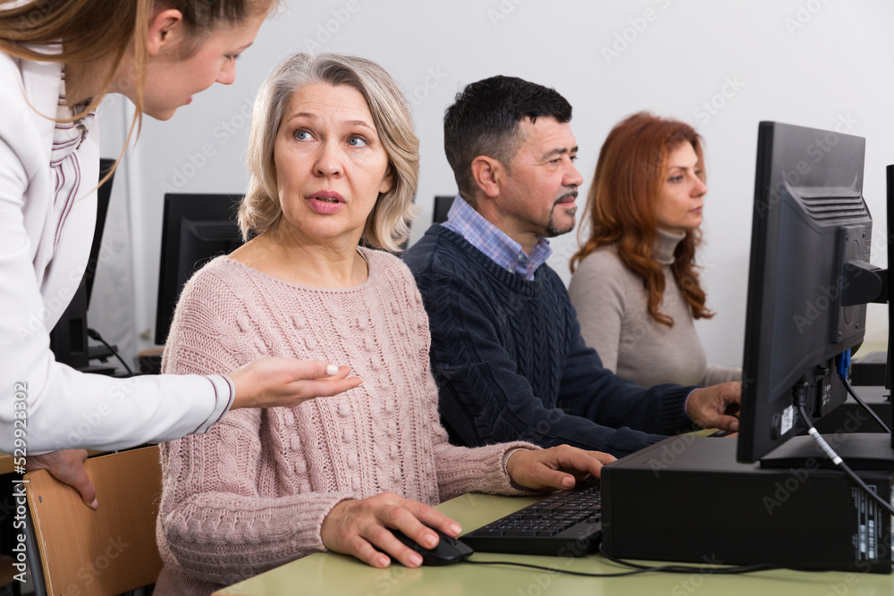 Business woman helping to partners, pointing at computer monitor in office