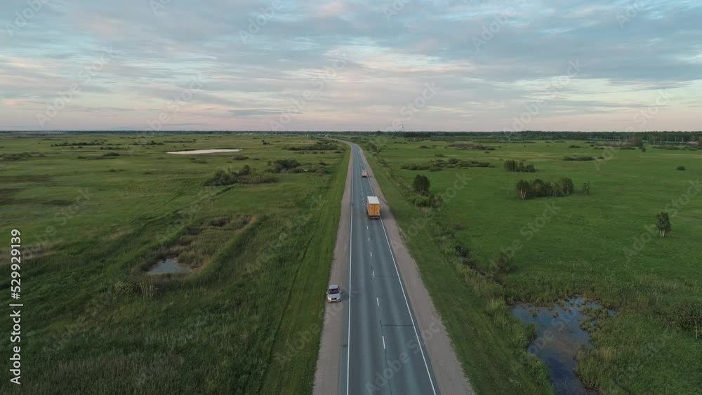 Aerial view of an intercity road with traffic between green fields in marshland. Beautiful summer landscape. Aerial view of an intercity road with traffic between green fields in marshland. Beautiful summer landscape.