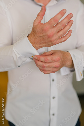 Man buttoning cufflinks in white dress shirt 