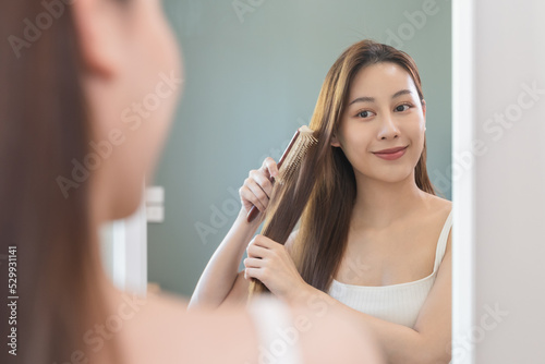 Lifestyles domestic routine for women, Asian woman blowing hair with hairdryer at home.