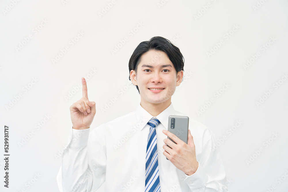 白背景でスマホを持って上を指差すビジネスマン 白背景でスマホを持って上を指差すビジネスマン