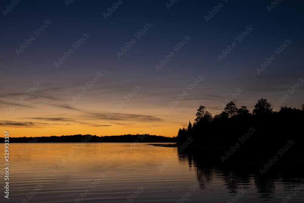 Fototapeta premium Fading sunset glow at dusk over northern lake scene for magazine newsletter advertising layout design