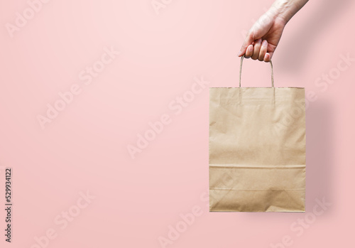 Woman's hand holding an empty brown paper bag. Packaging template mock up. Recycled, eco friendly, and shopping concept