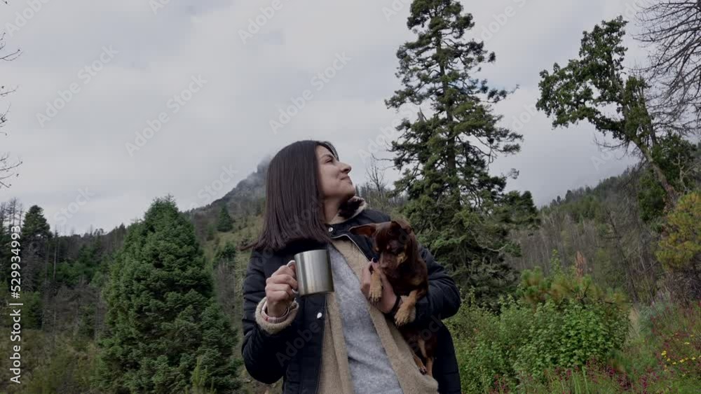 young woman with her pet drink coffee in the forest on a cold day young woman with her pet drink coffee in the forest on a cold day
