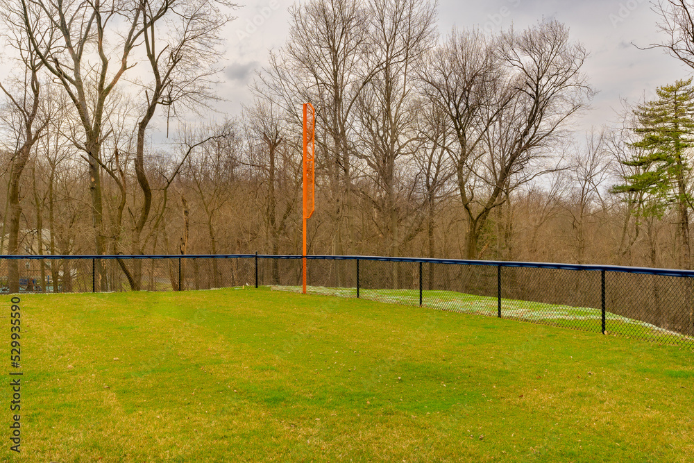 View of typical nondescript high school softball left outfield orange foul pole. No people visible. Not a ticketed event. View of typical nondescript high school softball left outfield orange foul pole. No people visible. Not a ticketed event.