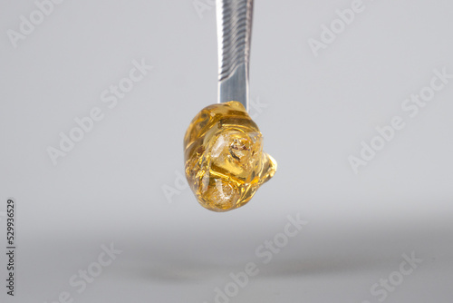 amber yellow cannabis wax concentrate dripping from the dabbing tool close-up
