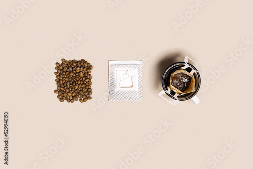 Drip coffee bag in cup, ground coffee and coffee beans,  pack with paper bag drip coffee filter, beige color background, minimal flat lay, pastel color, stages or steps of brewing coffee