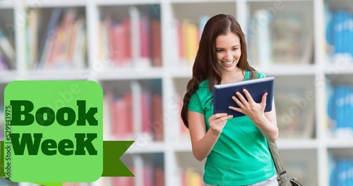 Book week text over smiling caucasian teenage girl reading book with bookshelf in background