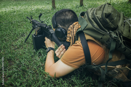 PMC soldier lying down shooting M249 SAW Light machine gun 7.62 mm photo