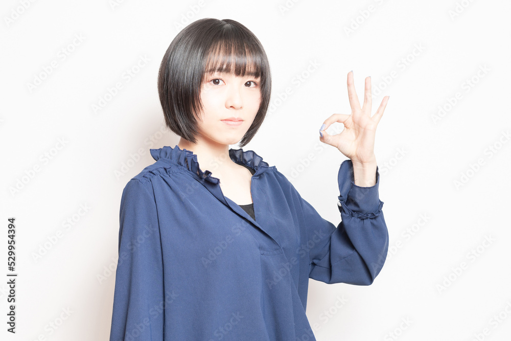 白背景の前でOKのポーズをする若い女性 白背景の前でOKのポーズをする若い女性