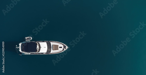 Aerial yacht on calm sea. Luxury cruise trip. View from above of white boat on deep blue water. Aerial view of rich yacht sailing sea. Summer journey on luxury ship.