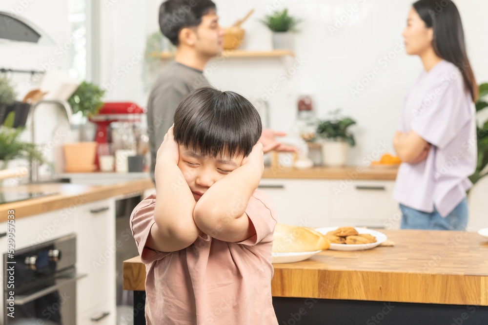 Little asian sad boy, unhappy while parents fighting, kid son not listen to shouting noise while mom and dad arguing, quarrel behind. Family suffering, stressed. Violence and divorce couple concept.