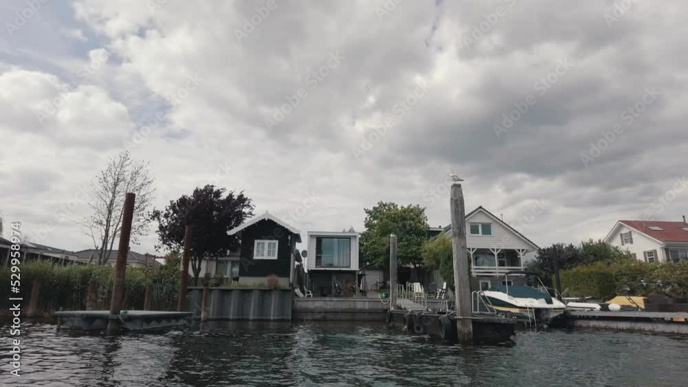 passing by some houses with personal docks at the waterside in The Netherlands passing by some houses with personal docks at the waterside in The Netherlands