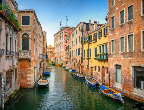 View on the narrow cozy streets of the canals with parked boats in Venice, Italy. Architecture and landmark of Venice. © Tortuga