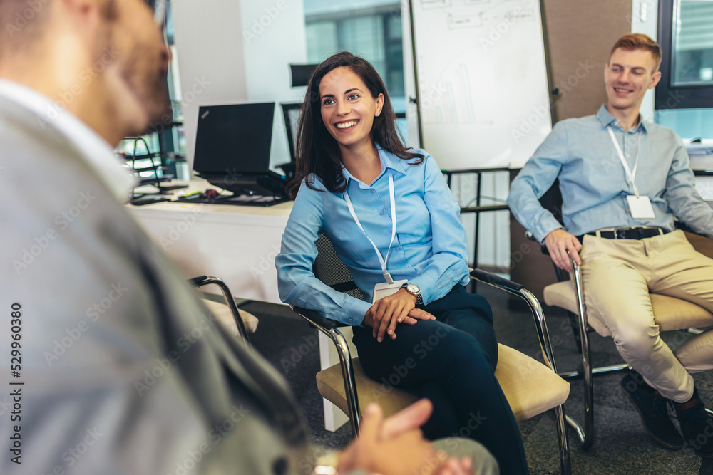 Confident young businesswoman with accreditation badge around her neck talking with colleague at business event Confident young businesswoman with accreditation badge around her neck talking with colleague at business event