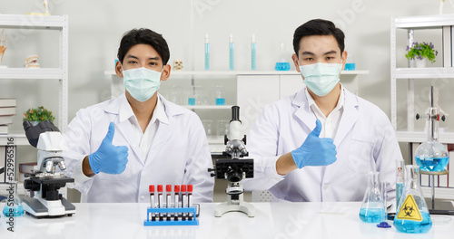 Two Male Scientists with Mask working in Lab while posing thumb up. SARS-CoV-2 , Covid-19 THEME.