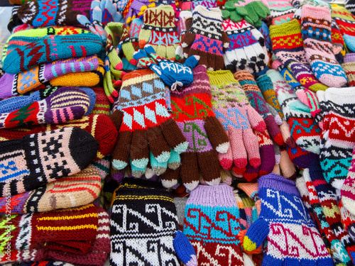 Many colorful knitted clothing in the form of mittens, gloves. Lots of mittens, gloves for cold seasons. Bright mittens and gloves are piled up as a texture background. Top view