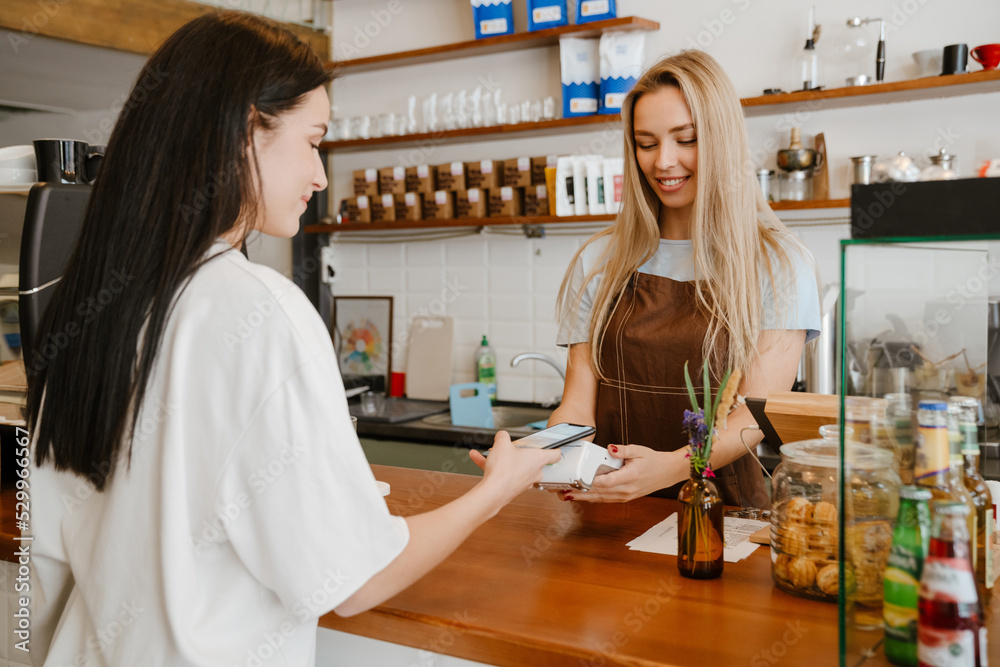 Obraz premium White brunette woman using cellphone while buying coffee in cafe