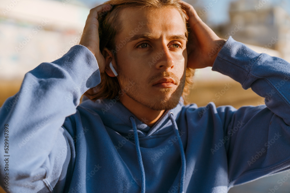 Obraz premium Young blonde man listening music while working out on sunrise