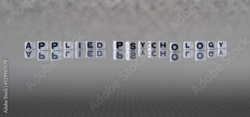 applied psychology word or concept represented by black and white letter cubes on a grey horizon background stretching to infinity