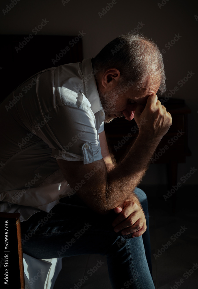 Portrait of adult man sitting on bed against window with sunlight and shadow Portrait of adult man sitting on bed against window with sunlight and shadow