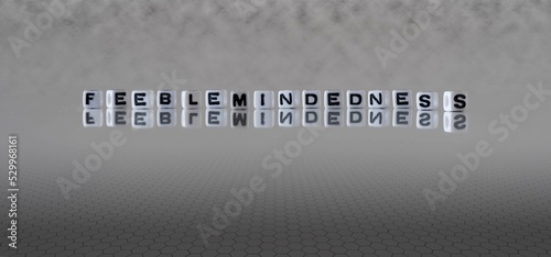 feeblemindedness word or concept represented by black and white letter cubes on a grey horizon background stretching to infinity photo