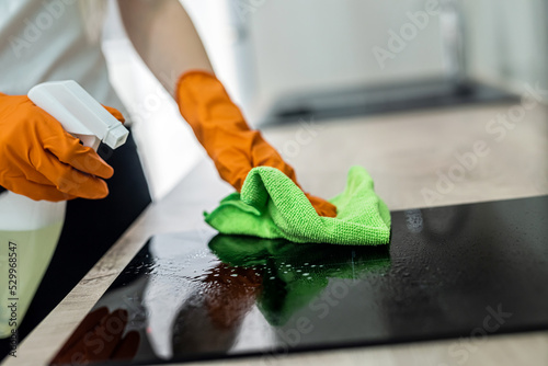 Φωτογραφία beautiful female hands in orange mittens wipe the kitchen surface