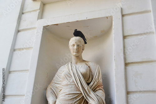 An ancient statue of a woman with a dove on her head