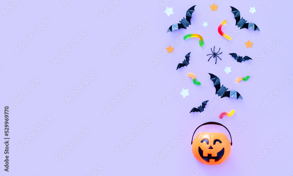 composition on the theme of the holiday halloween bucket pumpkins sweets bats spiders on a purple background with a place for text	
