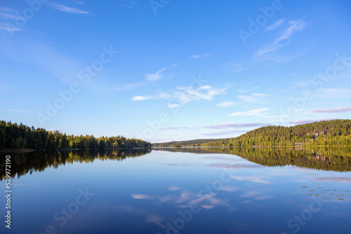 Fototapeta Naklejka Na Ścianę i Meble -  Calm evening at the lake shore in Finland. Beautiful scenery with green leaves in the forest.